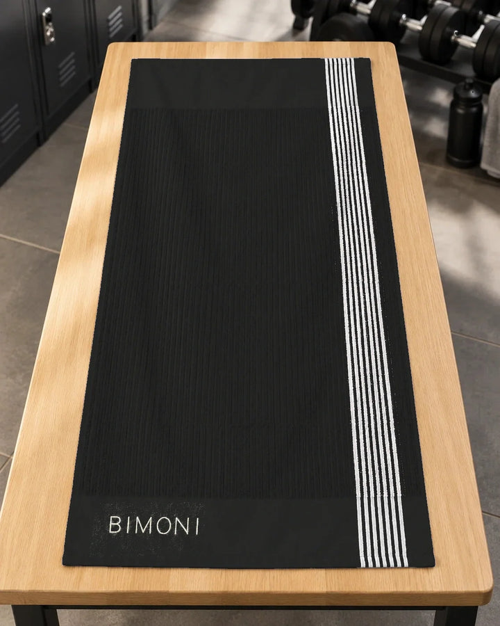 BIMONI serviette – Noir – Posée à plat dans l’espace fitness
